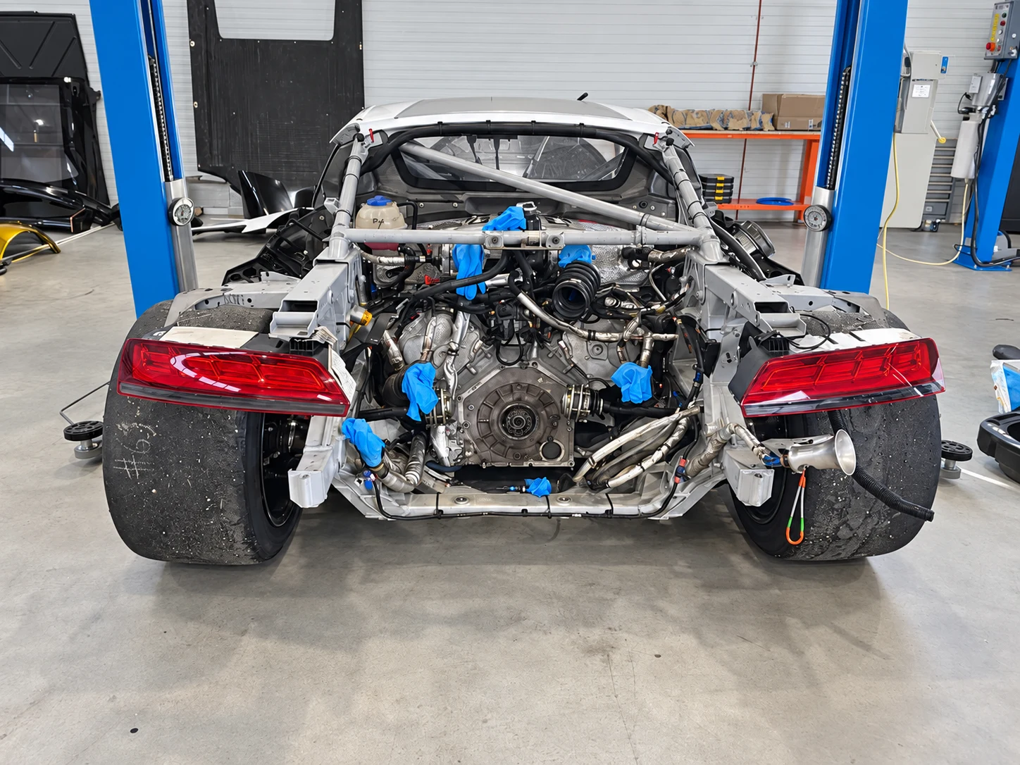 Audi R8 versenyautó leszerelt hátsó karosszériaelemekkel, műhelyi felkészítés közben