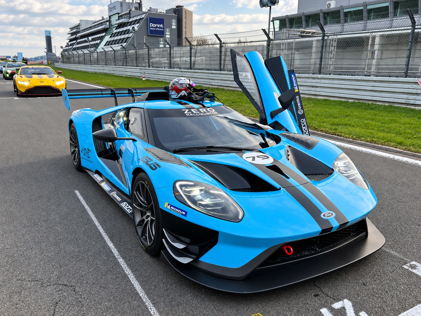 Kék Ford GT versenyautó nyitott ajtóval a versenypályán
