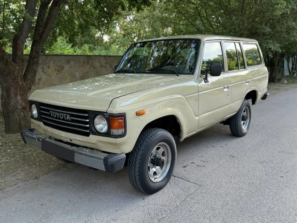 Az elkészült bézs Land Cruiser elölről és oldalról, egy fákkal szegélyezett úton