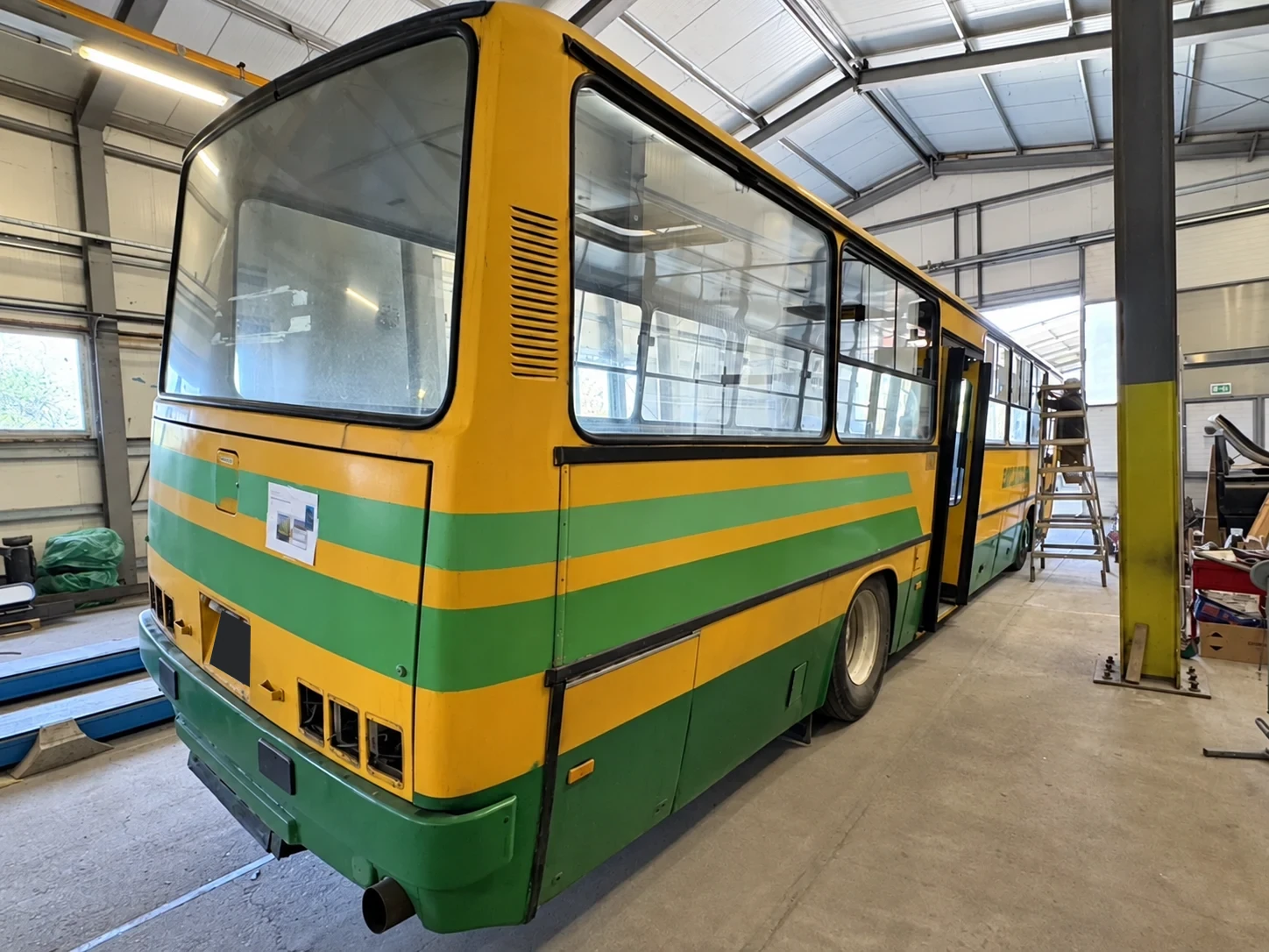 Sárga-zöld Ikarus busz műhelyi átalakítás közben