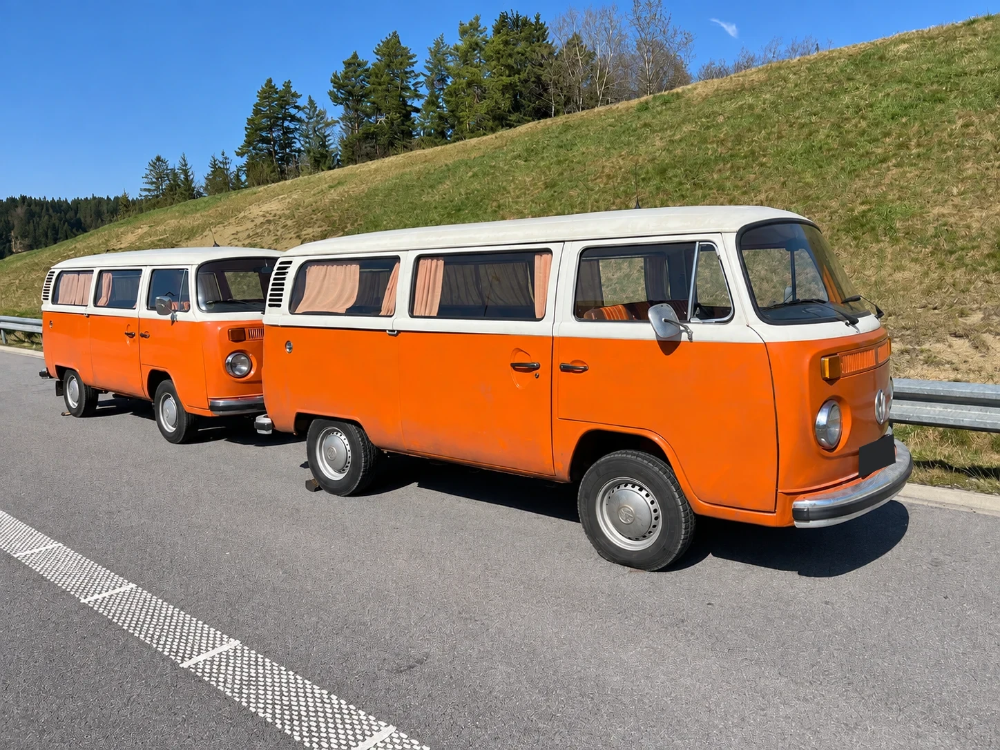 Két egyező narancssárga-fehér Volkswagen T2 minibusz egymás mellett